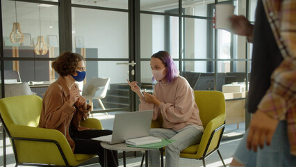 Sitting in the rest zone during breaking time, two girls-students are discussing together about their project, slow motion