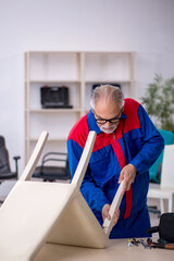 Old male carpenter repairing chair