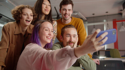 A group of five students are taking funny photos together, being in the auditorium in the university 