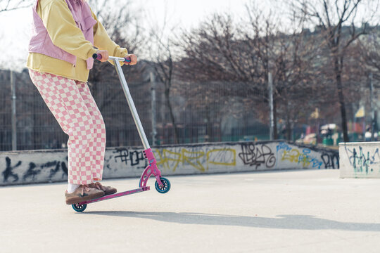 Young European woman drives a pink scooter on the skateboard ground active lifestyle concept no face visible copy space full shot . High quality photo