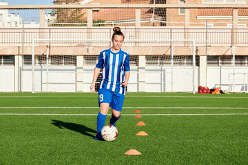 A female soccer player is training on a soccer field
