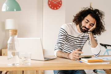Bored young man using his cell phone at home office