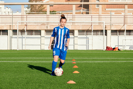 A female soccer player is training on a soccer field