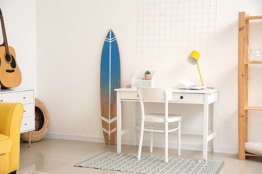 Interior of modern stylish room with surfboard and table with chair
