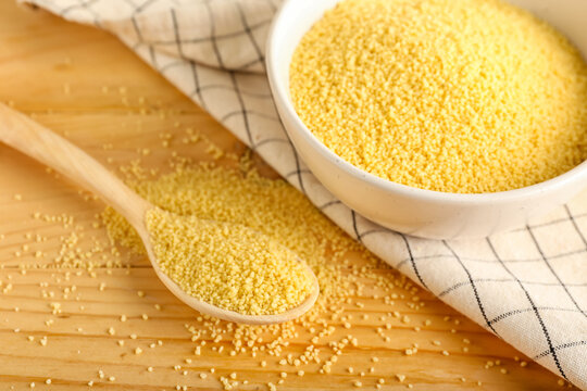 Bowl and spoon with raw couscous on table