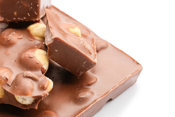 Pieces of tasty chocolate with hazelnuts on white background, closeup