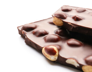 Pieces of tasty chocolate with hazelnuts on white background, closeup