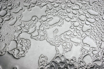 Regenwasser auf einem Bistrotisch bilden ein abstraktes Muster