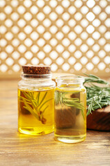 Bottles of rosemary essential oil on wooden background