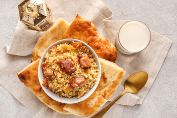 Bowl of tasty Asian pilaf and flatbread on grunge background