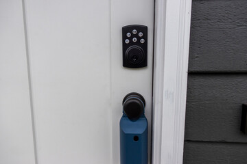 View of a white door with keypad entry and a real estate lock box around the door knob