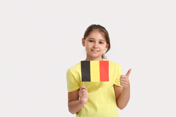 Little girl with flag of Belgium showing thumb-up on light background