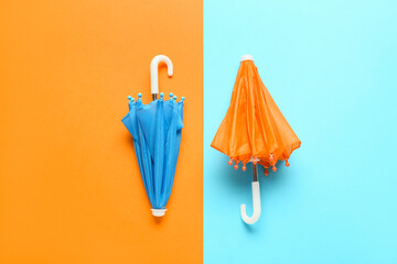 Two small umbrellas on color background