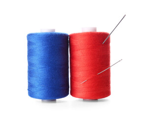 Red and blue thread spools with needles on white background