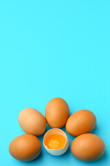 Cracked and whole chicken eggs on blue background. Concept of uniqueness