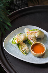 Vegetables wrapped in rice pancake on a gray plate