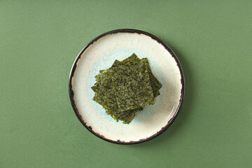 Plate with tasty seaweed sheets on green background © Pixel-Shot