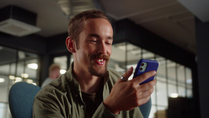 A young man-student sits on the chair and talking to his friends on the video call, close up 