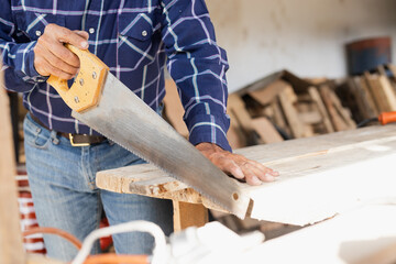 Hands of a carpenter man working with the saw in the wood - detail of the hands of a working man