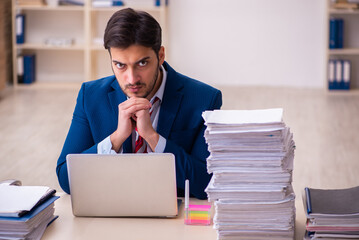 Fototapeta premium Young businessman employee unhappy with excessive work in the office
