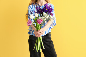 Young woman holding beautiful flowers on color background