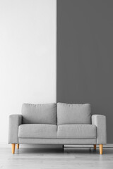 Comfortable grey sofa near black and white wall