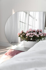 Begonia flowers and modern laptop on floor near bed