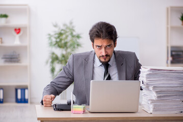 Obraz premium Young male employee and too much work in the office