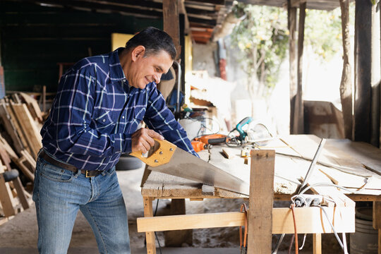 Hispanic man working with saw in his carpentry workshop-Latin Carpenter working