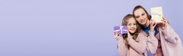 happy kid and cheerful mother holding presents isolated on purple, banner.