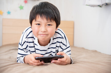 子供部屋でスマホを見ているアジア人の男の子