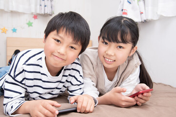 子供部屋でスマホを見ているアジア人の子供
