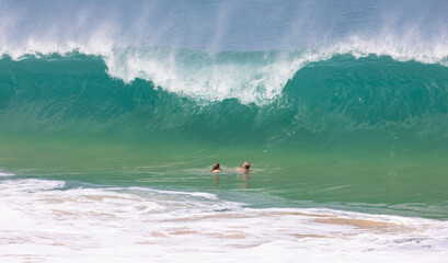A couple swimming in Waimea Bay about to be crushed by a giant wave