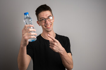 One man young caucasian male wearing black posing happy smiling with plastic bottle of water studio...