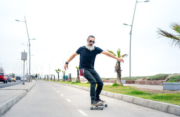 latin senior man skateboard on bikeway and having fun in La Serena