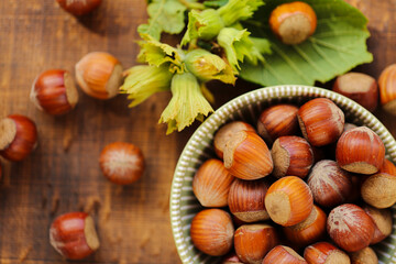 Hazelnuts close-up in a green cup on a wooden table. Whole nuts with green leaves. Fresh harvest of hazelnuts. organic ripe hazelnuts. Healthy fats.Hazelnuts harvest.view from above. 