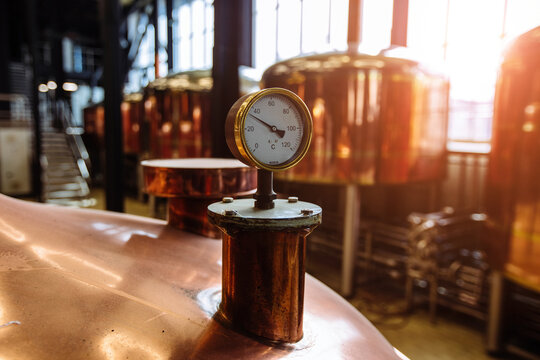 Thermometer or pressure gauge on copper colored brewery tanks close up - Powered by Adobe