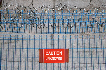 Iron fence with barbed wire. Metallic fence with red warning sign Unknown.