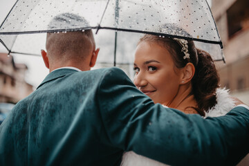 Wedding happy moments. Happy young couple, newlyweds walking the streets in rainy weather while...