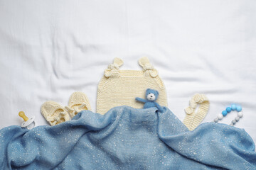 Flat lay composition with child's clothes and accessories on white fabric, space for text