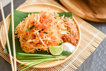 Thai food fried noodle Thai style with prawns bean sprout and garnish peanuts chili powder sugar lemon lime, Stir-fry noodle Pad Thai on plate served on the dining table food