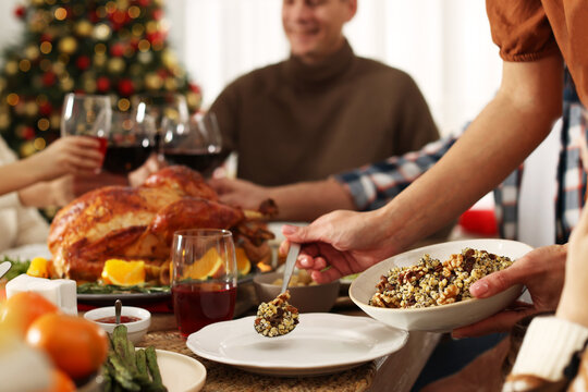 Mother putting traditional Christmas kutia onto her daughter's plate at festive dinner, closeup. Slavic dish