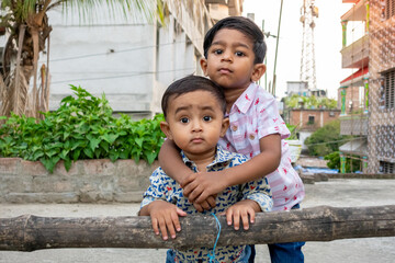 Two Asian cute baby boys standing on the rooftop. Two brothers are hugging and caressing each other.