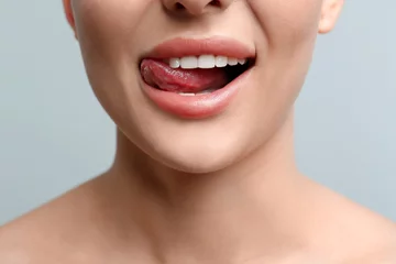 Woman licking her lips on light background, closeup © New Africa
