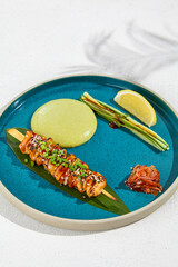 Squid yakitori in ceramic dish on white background. Japanese skewered squid with wasabi sauce. Grilled kalmar on bamboo skewer in asian style. Food menu for izakaya. Summer pan asian menu. © Ryzhkov