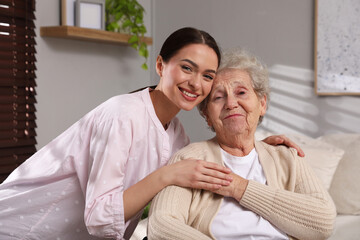 Portrait of young caregiver and senior woman indoors. Home care service