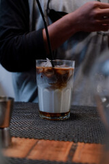Ice coffee with cream in a tall glass on dark concrete table on cafe