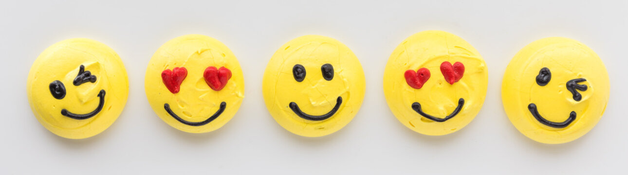 A row of smiley face emoji or emoticon merengue cookies.