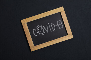 Blackboard with word Covid19 on black background, top view