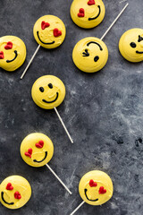 Several emoticon merengue cookies scattered against a dark background.
